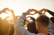 © Studio Romantic - Hands of team forming heart shapes, raised towards sky with sun shining, friends people gathering expressing love and unity, collective joy and connection, positive emotion togetherness outdoor