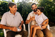 © kleberpicui - Grandfather, adult son and young grandson sitting outdoors and interacting with affection, representing family bonding and multigenerational connection.