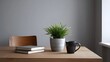 © Bussakon - A minimalist interior scene features a stack of books a potted plant and a dark mug on a wooden desk suggesting a quiet workspace or study
