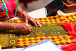 © Roger - African tailor's hands marking colorful ankara fabric with chalk on a workspace