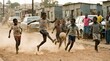 © Weiming - Joyful African Children Playing Energetic Soccer on a Dusty Township Street