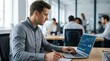 © Justlight - Medium shot of a financial analyst reviewing detailed charts and graphs on a laptop the screen in sharp focus while the busy office background is blurred.