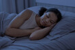 © Anastasiya - Young black woman sleeping peacefully in bed at night under blanket in cozy bedroom, representing rest, recovery, healthy sleep and calm domestic lifestyle environment