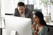 © fizkes - Experienced middle aged businessman mentor supervisor explaining digital task details on computer screen to young adult female colleague coaching intern onboarding new staff member at workplace desk
