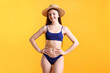 © New Africa - Beautiful young woman wearing stylish blue bikini and straw hat on yellow background