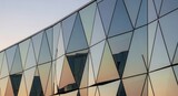 A large glass building with many triangular windows reflecting the sky architecture photography buil