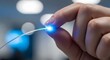© Ans Creative - Close-up of Hand Holding Fiber Optic Cable with Glowing Blue Light Representing High-Speed Internet and Data Transfer Technology