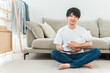 © buritora - A young Asian man holding a baby in his living room.