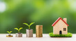 © Rifat - Small green plants growing on stacks of coins with a wooden house on grass growth money