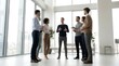 © Nest - A diverse group of blurred business professionals stands together in a bright, spacious modern office lobby or open workspace, engaged in casual conversation and networking.