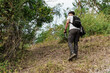 © Jordan - Young man hiking uphill through green forest outdoors