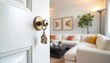 © Viktor - Open white door with brass knob reveals keys with house charm. Blurred interior living room with sectional couch coffee table and floor lamp. Home entry, real estate concept.