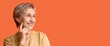 © Pixel-Shot - Beautiful mature woman with short hair on orange background with space for text