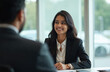 © Maryna - Two Indian professionals, a man and a woman, sit at a table discussing business. They appear engaged in a positive conversation, possibly a meeting or interview.
