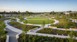 © Arip - Modern urban park with a prominent circular green lawn, surrounded by winding paved pathways and contemporary landscaped garden beds, designed for relaxation and community.