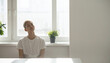 © Teeradej - Mental wellness, depression. Young person sitting by window with plants, wearing white shirt, in bright, minimalist room