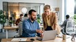 © TheseusStock - Two professional colleagues collaborating over a laptop in a modern open-plan office.