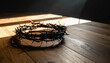 © ARVD73 - Crown of thorns on a wooden table in a dark room, soft window light, dramatic shadows, minimal composition, copy space, symbolic Christian Easter concept.