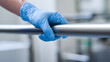 © A2Z AI  - A hand in a blue protective glove grips a clean metal bar, signifying hygiene, safety, and careful handling in a controlled environment