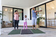 © wavebreak3 - African American family stretching with child in sportswear on yoga mats on patio by sliding doors