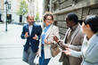 © Marko Geber - Diverse business colleagues walking and talking on city street