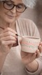 © Alina - Elderly woman decorating handmade ceramic cup. Creative workshop and active senior lifestyle