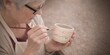 © Alina - Elderly woman decorating handmade ceramic cup. Creative workshop and active senior lifestyle