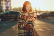 © SHOTPRIME STUDIO - Woman with coffee and phone smiling on urban street at golden hour, candid lifestyle portrait in beanie and plaid coat, authenticity and emotional storytelling for mindful living.
