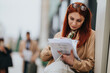 © qunica.com - A business woman reads and organizes documents while waiting at a transit stop. A professional worker reviews papers and prepares for a meeting during her commute.