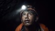 © Giacomo - Young miner with headlamp underground. Close-up of a wet face under helmet light in a dark tunnel, mining gear visible; concept of dangerous work and survival.