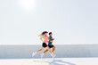© muse studio - Athletic woman and man running actively together side-by-side during a bright outdoor fitness session