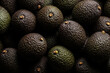 © IDNProdesign - Full frame close-up of ripe Hass avocados piled together with dark moody dramatic lighting showing textured skin and stems