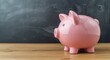 © AkuAku - Conceptual image of a pink piggy bank symbolizing education expenses with a chalkboard backdrop