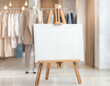 © Bold decisions - A blank white canvas on a wooden easel stand in a stylish clothing store, with a soft-focus background and copy space for a message or advertisement.
