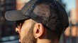 © mila103 - Man wearing black mesh cap on city rooftop in sunlight