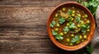 © vxnaghiyev - Hearty green pea curry served in an artisanal pottery bowl garnished with coriander leaves on a timber surface copy space