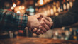 © Adobe Collections - Two men shaking hands in a warmly lit bar, signifying agreement and friendship.