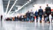 © morepiixel - A busy event space filled with people walking through an exhibition area, characterized by soft lighting and a blurred foreground.