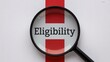 © Mudassir - Magnifying glass focuses sharply on the word eligibility placed over the flag of England symbolizing official scrutiny.