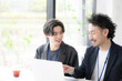 © kapinon - 会社の仕事中に一緒に打ち合わせする上司に励まされる新卒などの新入社員の爽やかなイメージ　その調子！仕事頑張ってね！OJTで先輩に指導を受ける若手社員の成長と教育のビジネスシーン　左にコピースペース