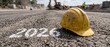 © Emanuel - Yellow Construction Safety Helmet on Asphalt with 2026 Marking Symbolizing New Year Industry Planning