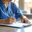 © Sarada - A woman in blue scrubs writing on a clipboard (1)