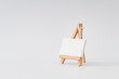 © Jakov Ilkoski - Blank canvas on wooden easel on white background. Minimal art mockup. Branding presentation idea. Creative copy space.