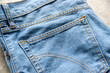 © Ramadhan - Close-up of a denim jeans back pocket with double orange stitching, showing detailed fabric texture and classic blue jean material. Casual fashion fabric