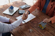 © MINAE - Business partners seal a property deal with a handshake over a wooden desk strewn with house models, keys, calculator and contract, symbolizing real estate transaction success