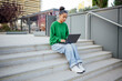 © Westend61 - Woman studying on outdoor campus stairs with laptop