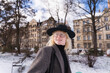 © Westend61 - Smiling young man with hat and blazer outdoors in snowy urban park