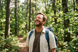© Anim - Happy man with backpack stands on trail in forest and enjoys nature.