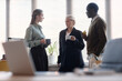 © TrueFrame Collective - Young adult Caucasian woman, senior woman, Black man discussing work during office coffee break, holding mugs and snack. Suitable for teamwork, corporate culture, staff communication