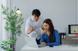 © Tj - Angry boss scolding a worried female employee working on laptop at her office desk, representing workplace conflict, stress, pressure, and toxic work environment dynamics